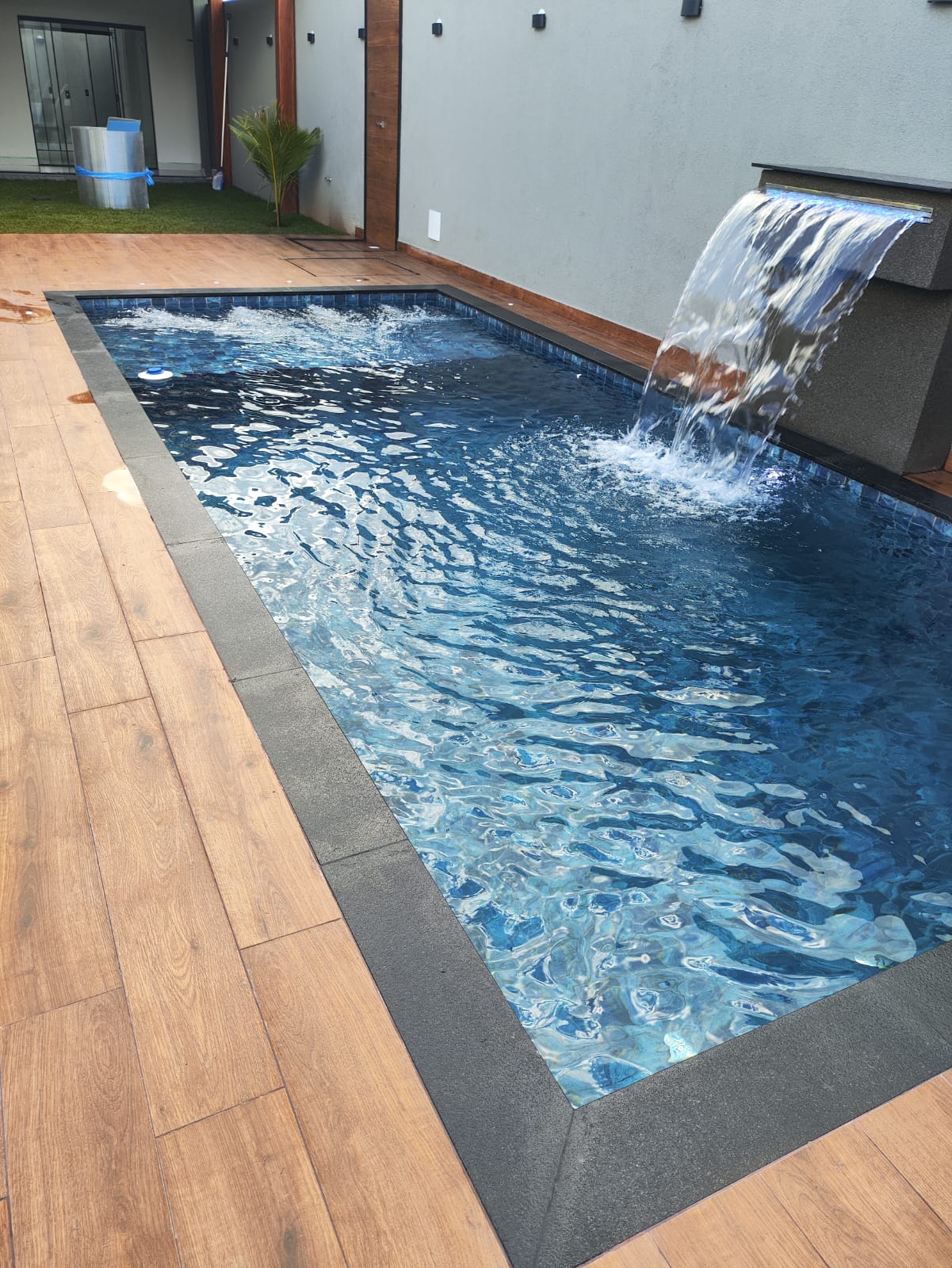 Piscina com cascata e deck de madeira